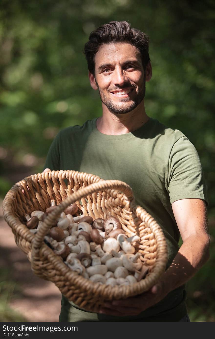 young man picking mushrooms in autumn forest