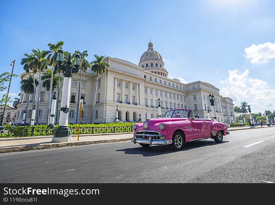 A vintage American retro carconvertible rides on an asphalt road in front of the Capitol in old town Havana. Tourist taxi cabriolet. A vintage American retro carconvertible rides on an asphalt road in front of the Capitol in old town Havana. Tourist taxi cabriolet.