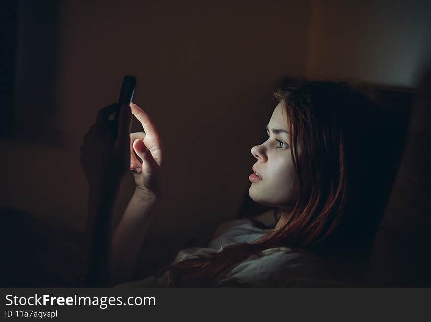 woman lies in bed at night with phone in hands emotions of communication