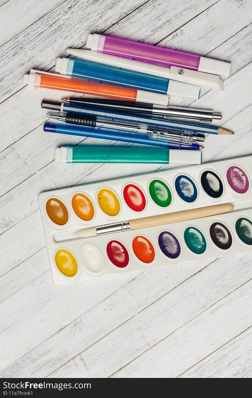 watercolor paints colored pencils and markers on wooden table top view. High quality photo