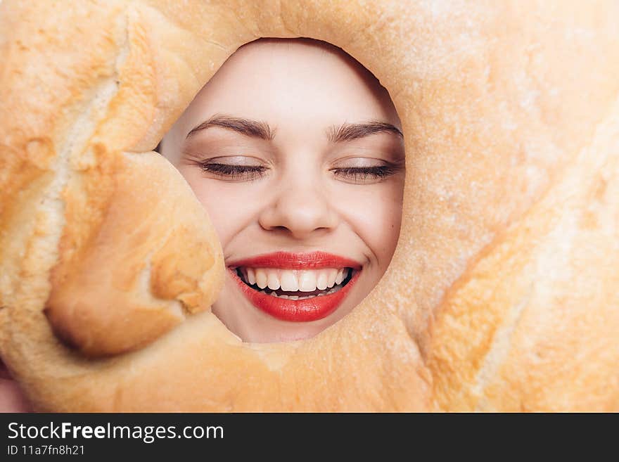 woman looking through the middle of a round loaf bright makeup close-up. High quality photo
