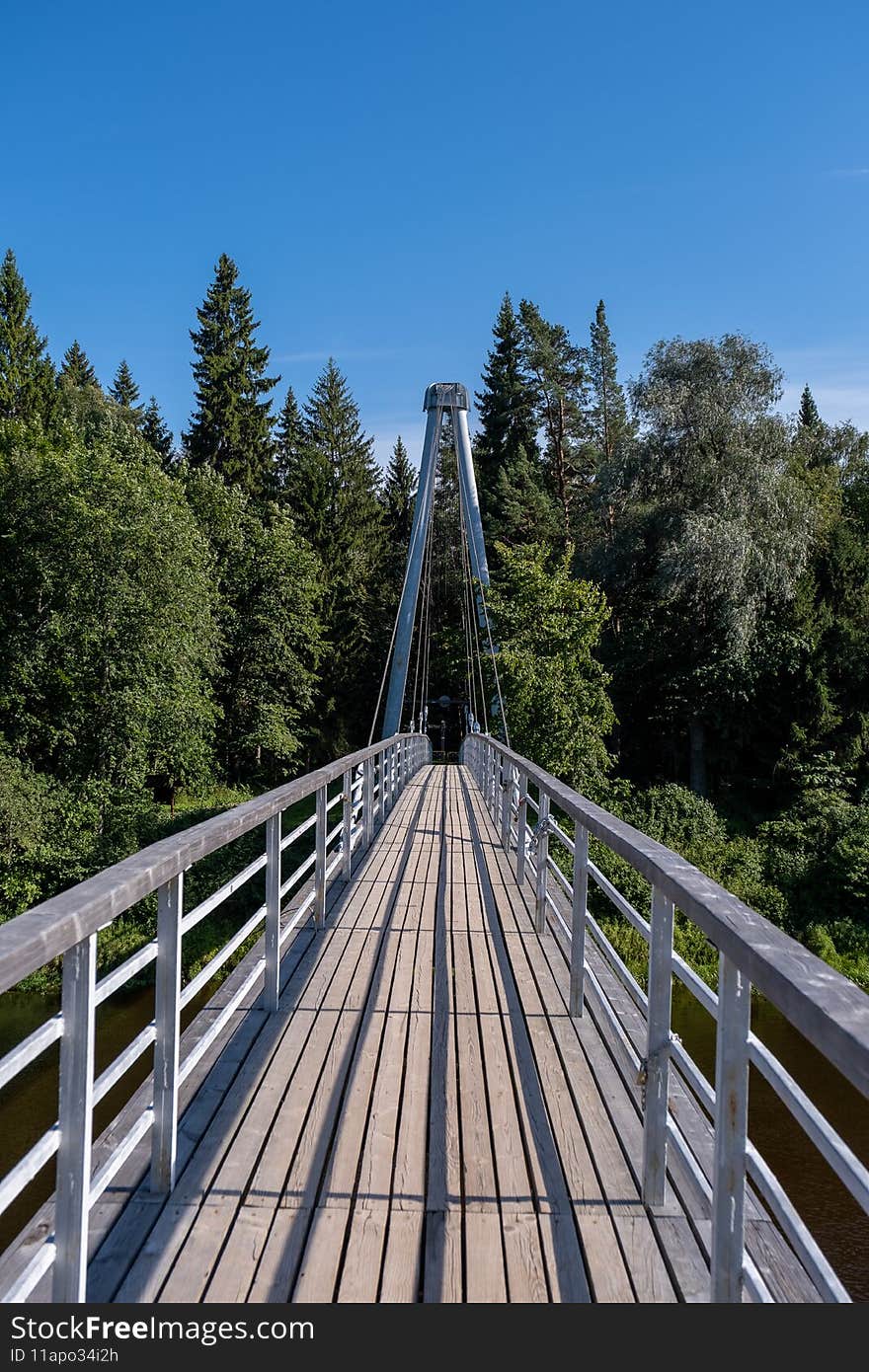 A little cable-stayed bridge that leads across the river and has a wooden plank floor