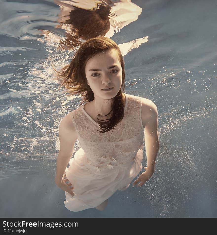 A girl in a white dress posing and somersaulting under water as if flying in zero gravity. A girl in a white dress posing and somersaulting under water as if flying in zero gravity