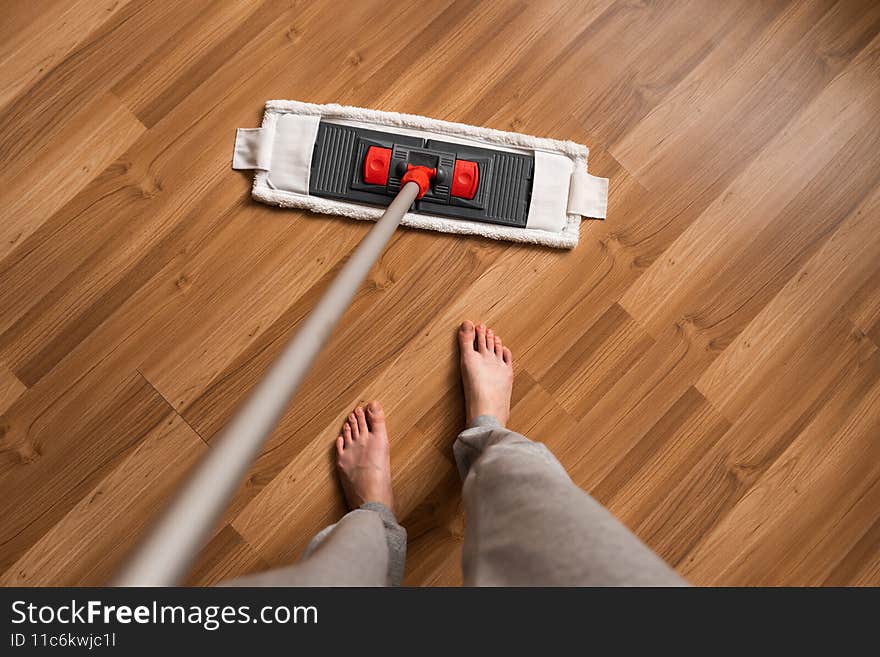 A woman cleans the floor with a mop. A woman uses a mop to clean the floor