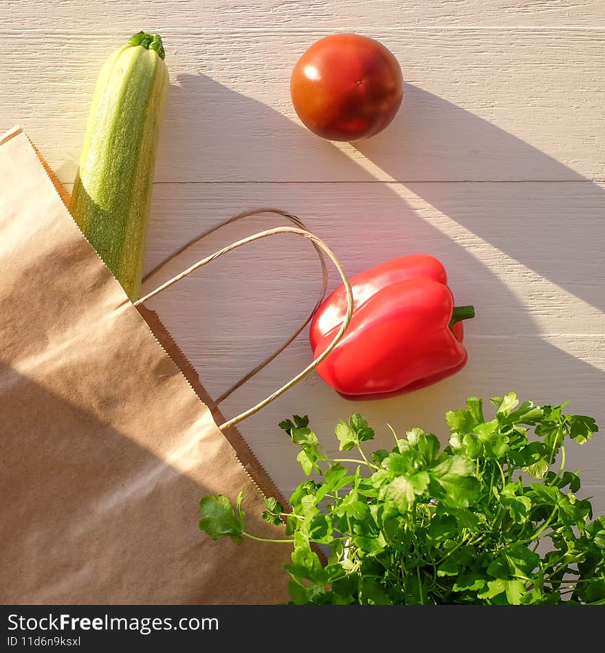 Vegetables in grocery eco bag on wood background, sunlight, square image. Top view.