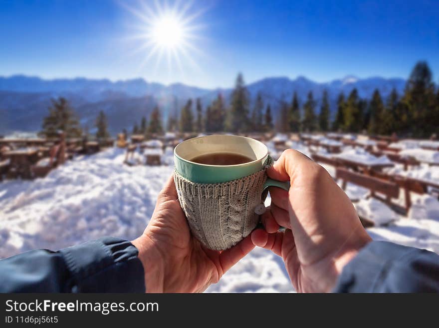 A cup of hot tea hold in hand with mountain view at winter