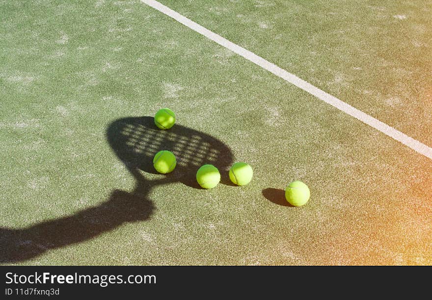 Shadow of a padel racket with a yellow ball on the green grass.