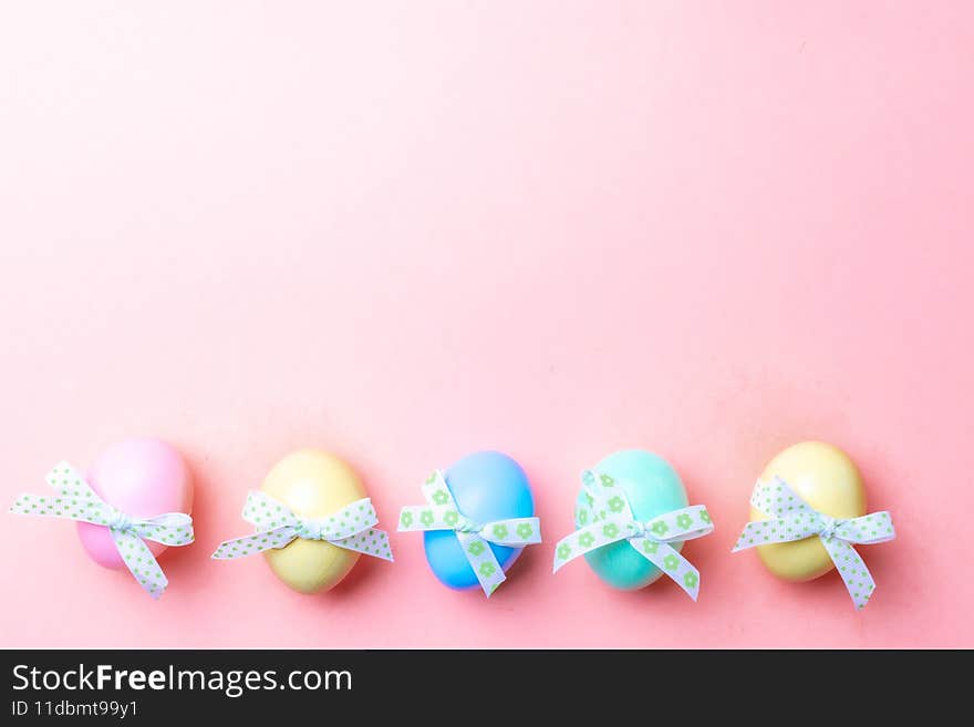 Easter holiday. Colourful egg with tape ribbon on pastel pink background in Happy Easter decoration. Spring holiday top view with