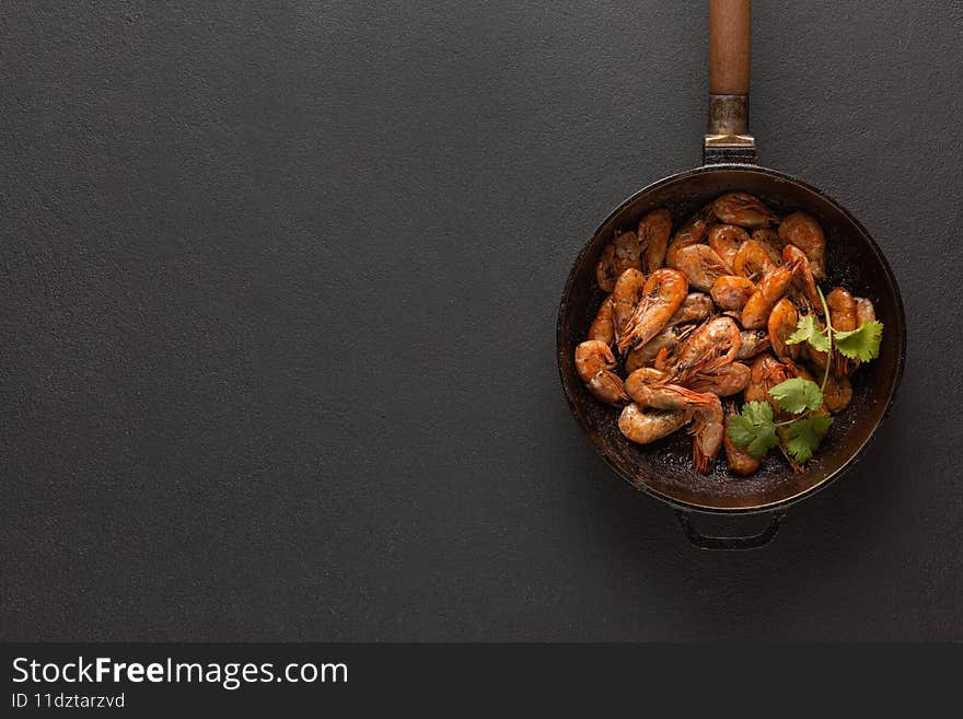 Fried shrimps in a pan with cilantro, top view