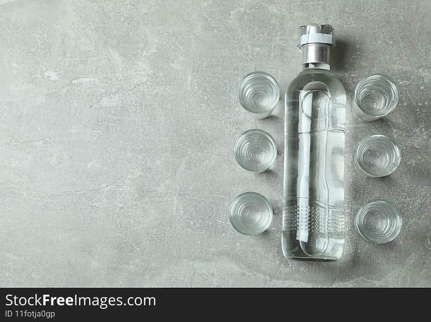 Blank bottle of vodka and shots on gray background