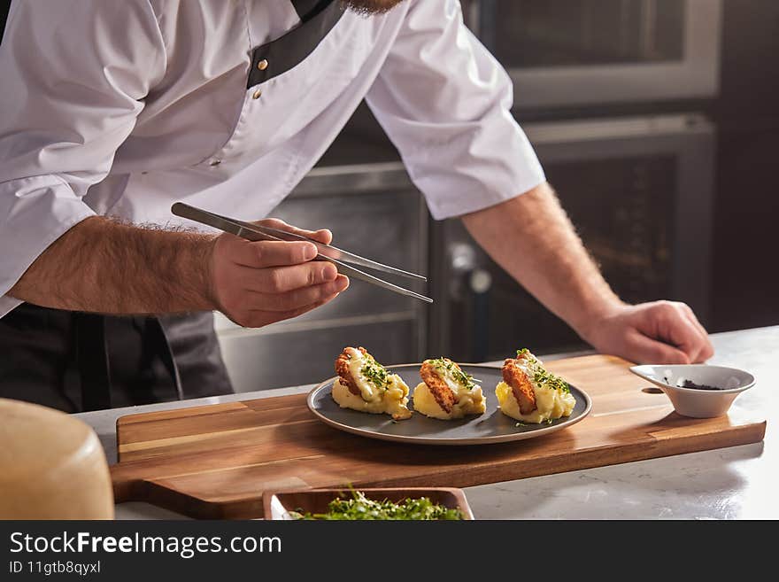 Cropped photo Close-up hands of male cook adding greens finishing dish, decorating meal in the end. gastronomy, food, nutrition, cafe concept