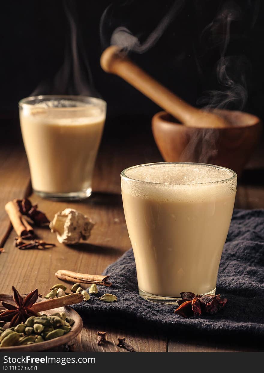 Masala tea is poured into a glass mug. Spices are laid out on the table. Masala tea is poured into a glass mug. Spices are laid out on the table