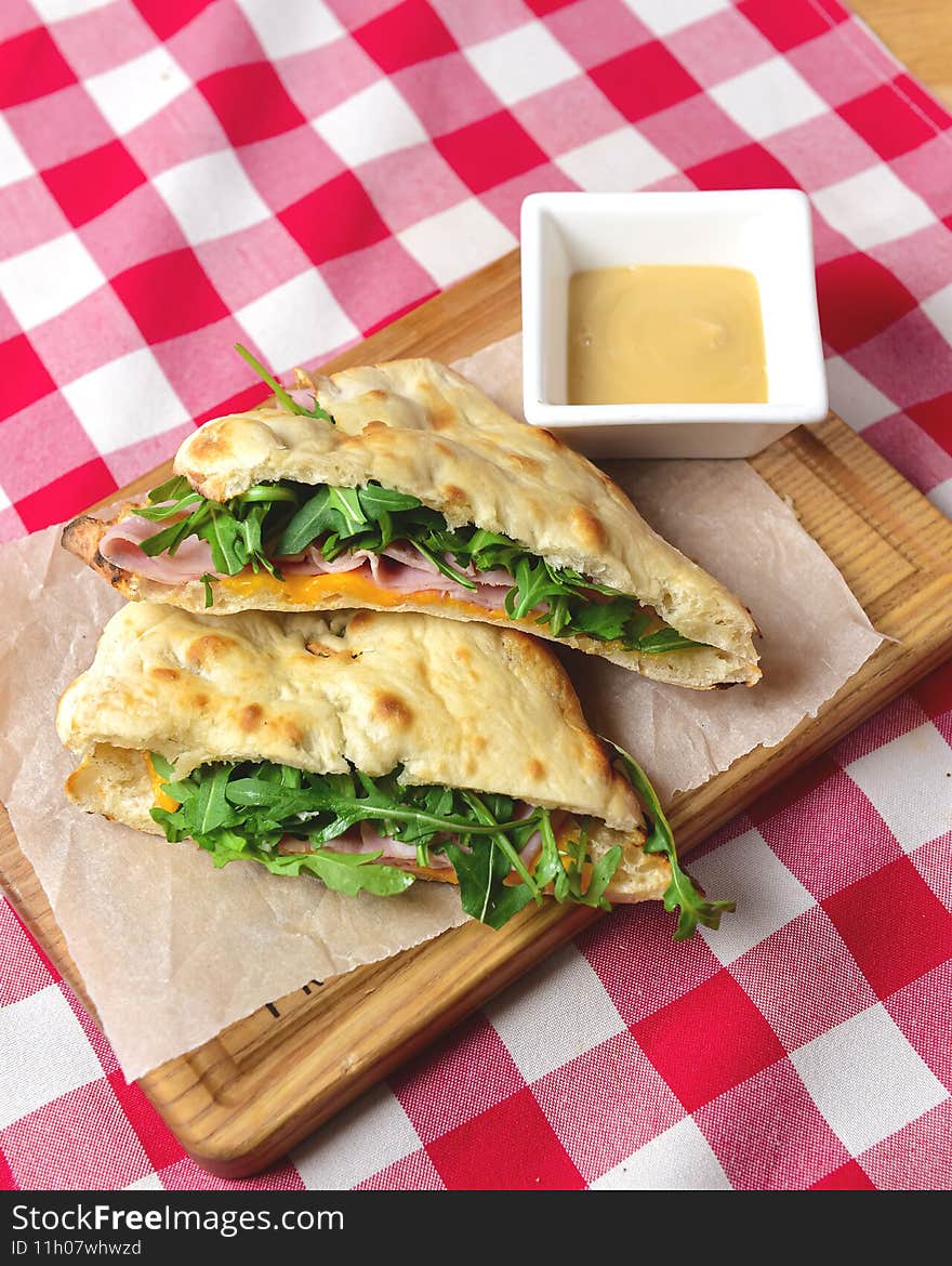 Ham and fresh vegetables in pita bread on wooden table with red plaid tablecloth. Delicious breakfast concept, Italian cuisine