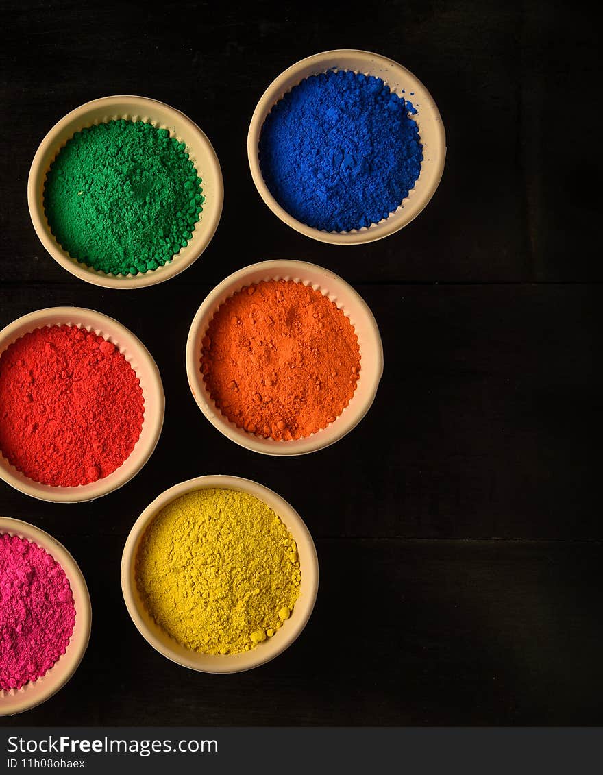 top view of colorful traditional holi powder in bowls isolated on dark background.Space for text . happy holi.Concept Indian color festival called Holi