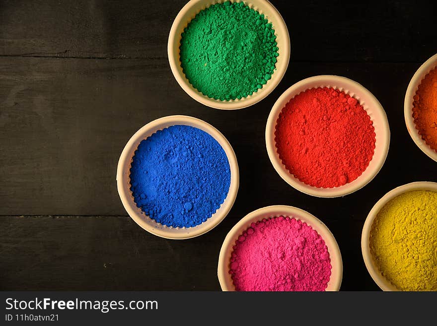 top view of colorful traditional holi powder in bowls isolated on dark background.Space for text . happy holi.Concept Indian color festival called Holi