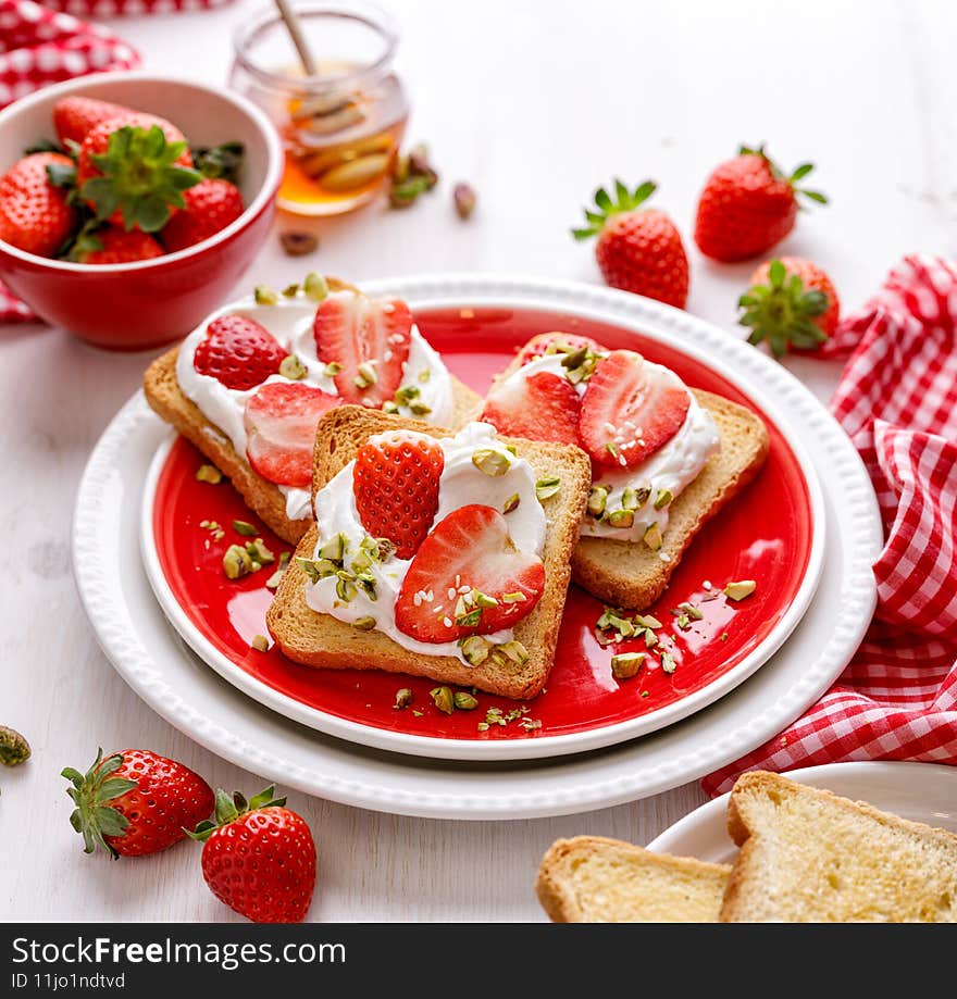 Delicious homemade toasts with strawberries and cream cheese sprinkled with pine nuts