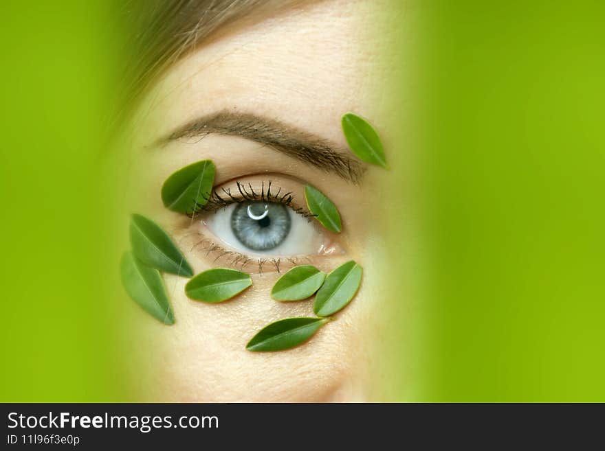 Closeup of young woman`s face with boxwood leaf patches.