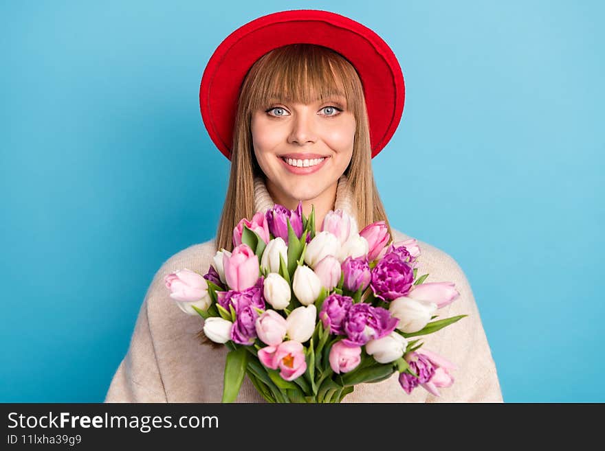 Photo of adorable satisfied person beaming smile hold flowers wear cap isolated on blue color background.