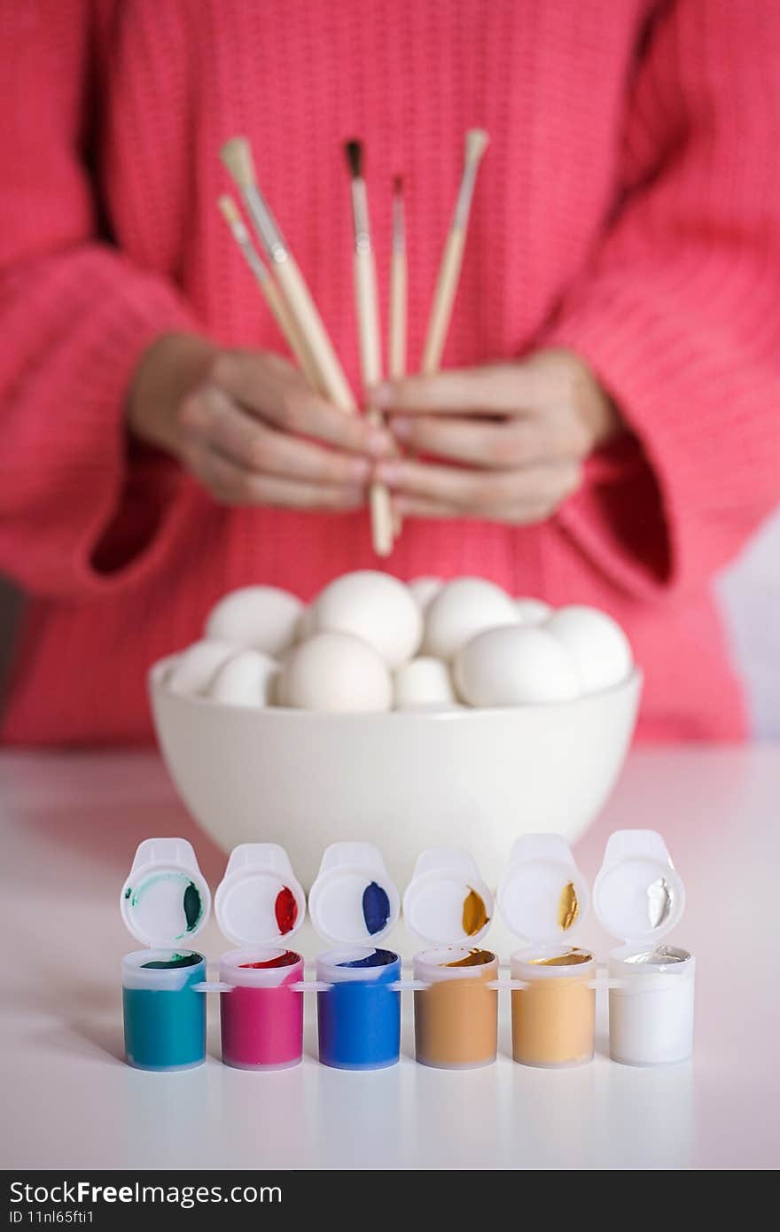 Girl holds brushes ready to paint eggs for Easter