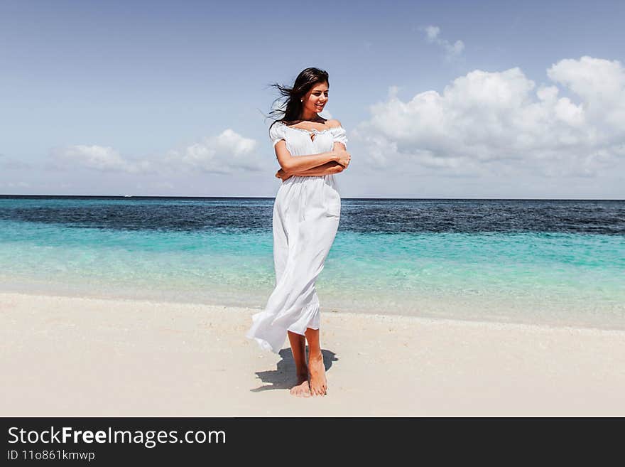 Woman in white dress walking on tropical beach, tropical sea on background. Woman in white dress walking on tropical beach, tropical sea on background