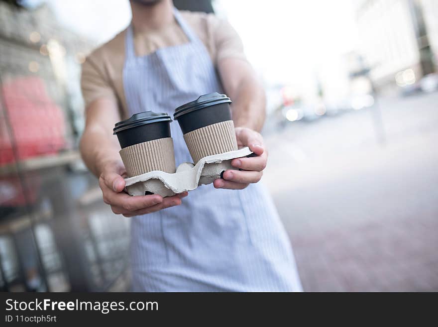 Coffee to go. Two glasses of coffee on stand in outstretched male hands, face is not visible. Coffee to go. Two glasses of coffee on stand in outstretched male hands, face is not visible