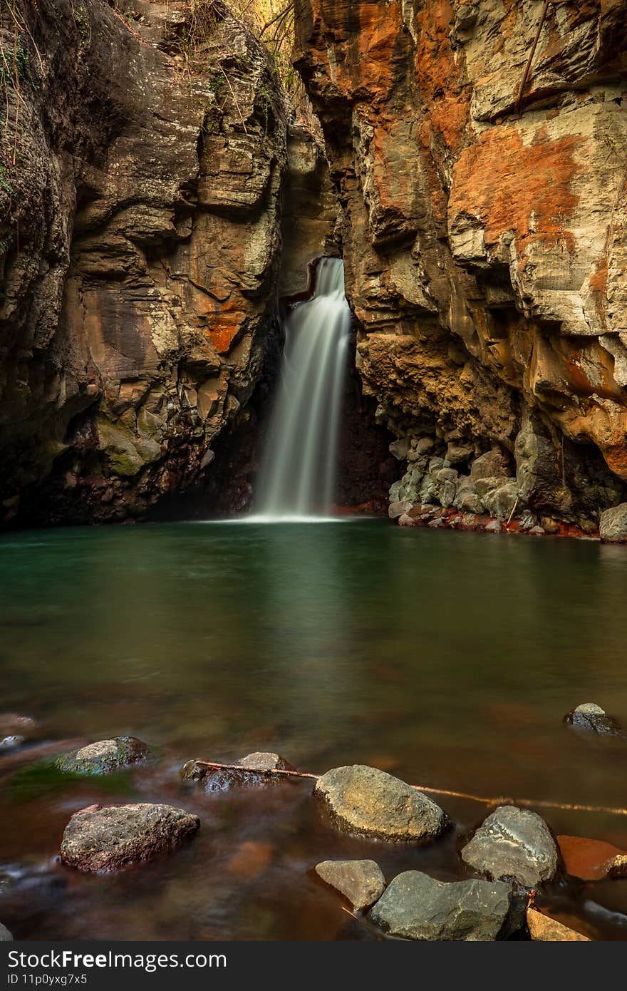 Waterfall surrounded by rocks. Beautiful landscape. Foreground with stones. Slow shutter speed, motion photography. Travel and adventure. Nature and environment. Waterfall Tembok Barak, Bali Indonesia