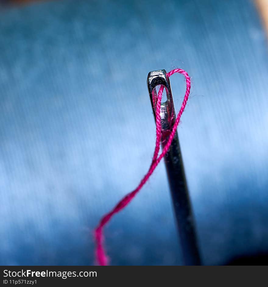 Thread with a needle on the background of spools of thread, sewing and needlework