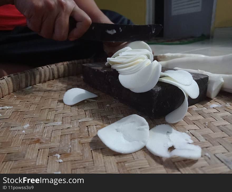 Photo of cassava being sliced with a knife with a good photo appearance and an angle that is in accordance with photography principles