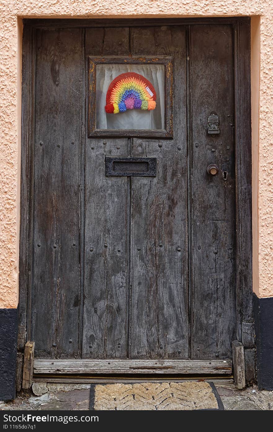 Old wooden door with rainbow during lockdown in Dulverton, England
