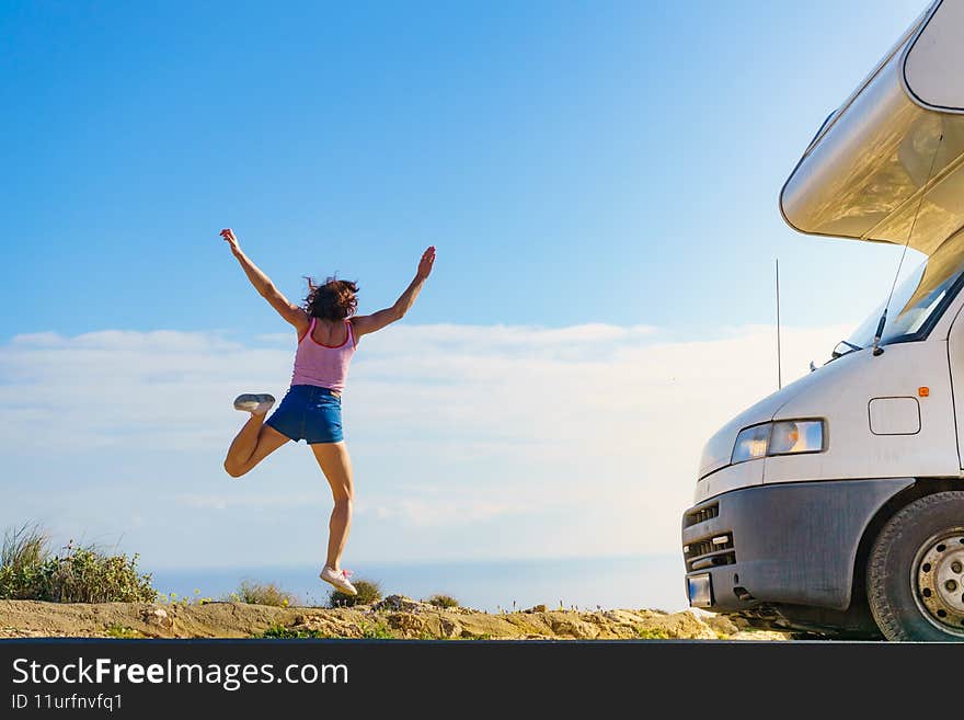 Woman enjoying trip with rv motor home, jumping in the air at camper car. Happiness, vacation and traveling. Woman enjoying trip with rv motor home, jumping in the air at camper car. Happiness, vacation and traveling