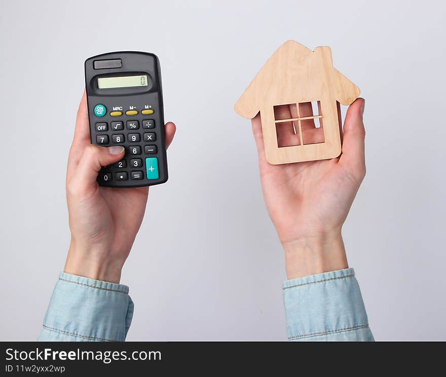 Calculation of the cost of housing, rent. Female hand uses calculator and hold house figure on yellow background. Top view. Calculation of the cost of housing, rent. Female hand uses calculator and hold house figure on yellow background. Top view