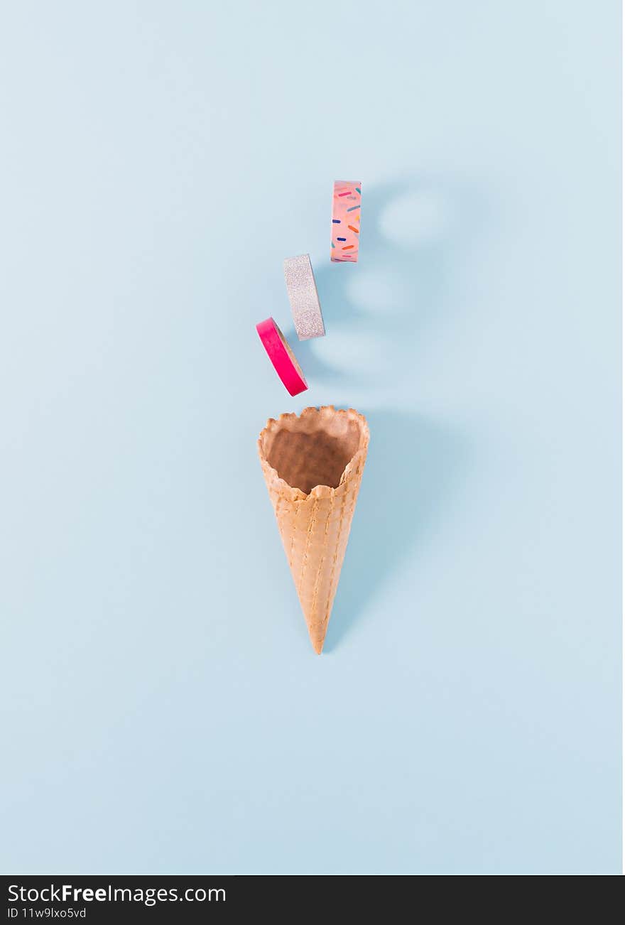 One cornet with vibrant and colorful adhesive tapes on a pastel blue background. Minimal conceptual flat lay idea.