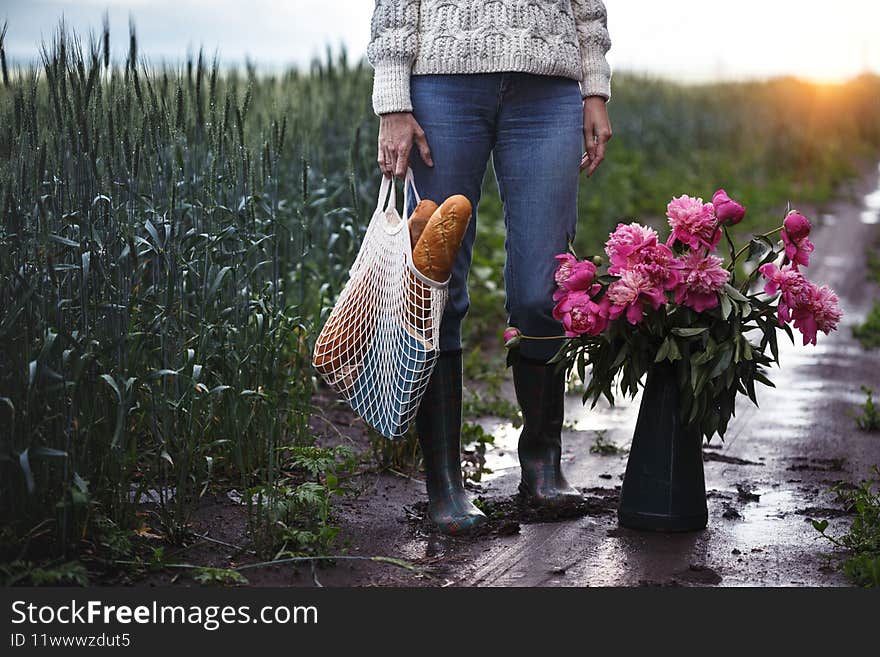 Girl with a bouquet of peony and a string bag with baguettes. spring mood and still life in the village. Girl with a bouquet of peony and a string bag with baguettes. spring mood and still life in the village
