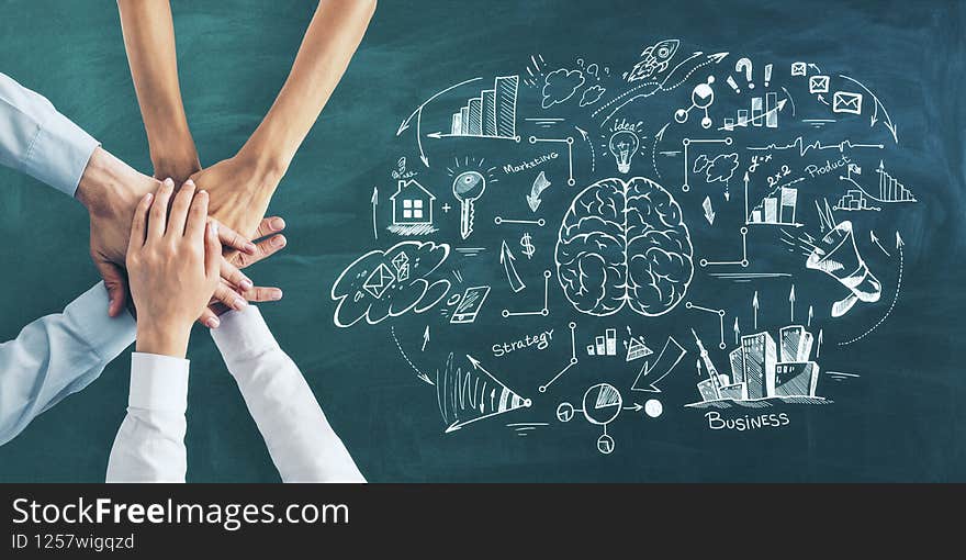 Business training concept with business people hands in a pile on green blackboard background with handwritten brain and business steps scheme