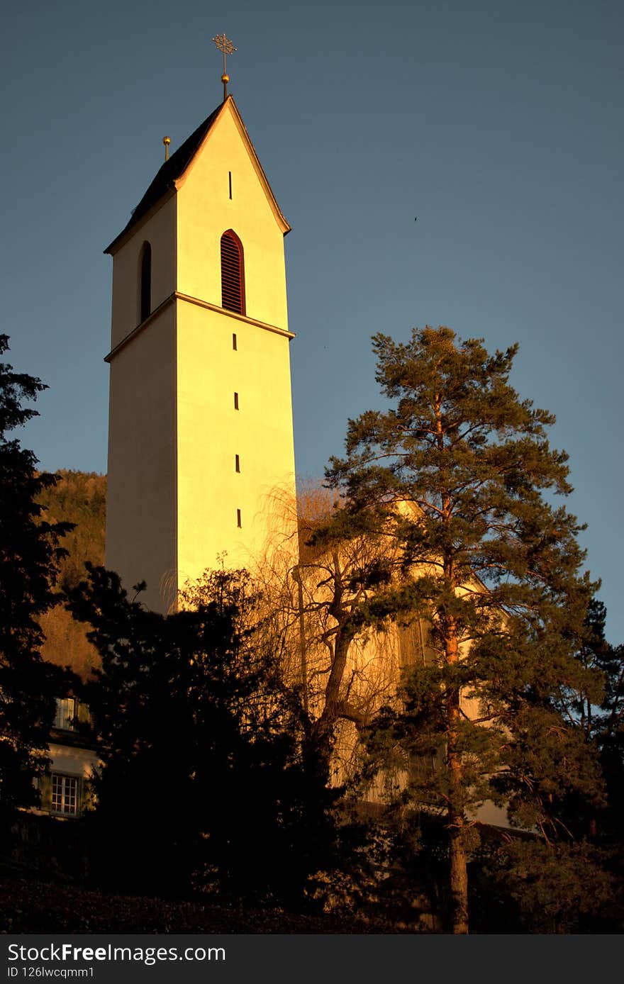 Majestic tower of a catholic church illuminated by the sun at dawn in Chur in Switzerland 20.2.2021. Majestic tower of a catholic church illuminated by the sun at dawn in Chur in Switzerland 20.2.2021