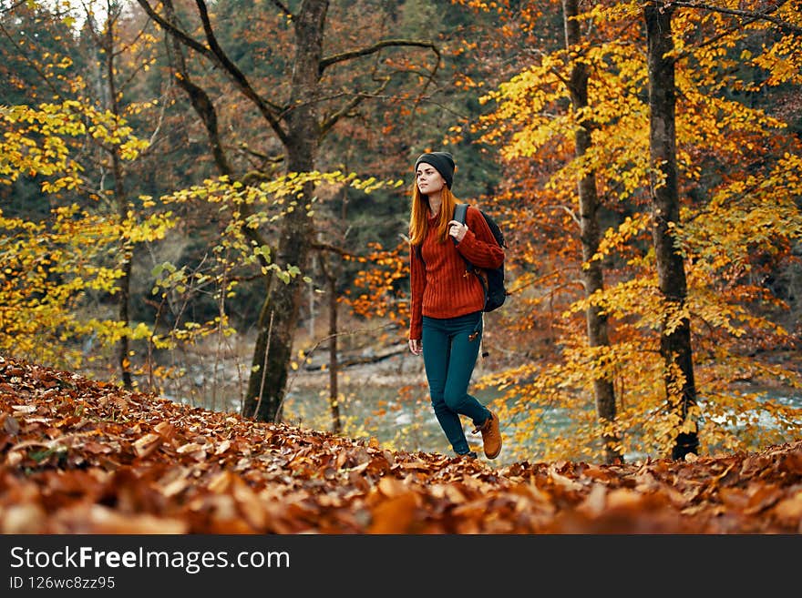 woman tourist walks through the park in autumn with a backpack on her back and tall trees landscape river lake. High quality photo