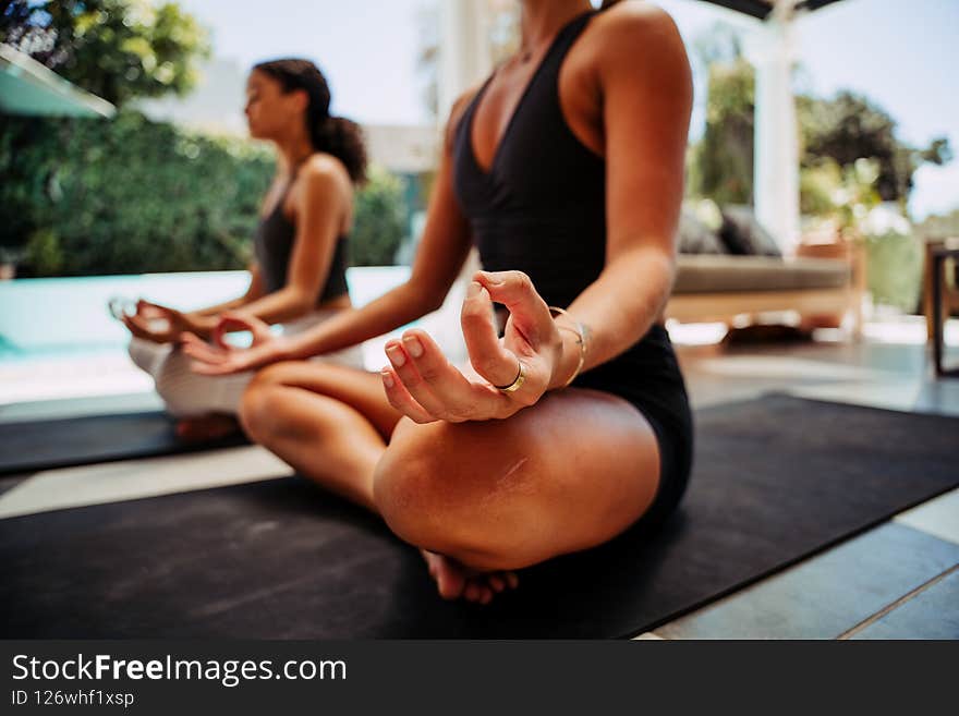 Two friends practicing meditation sitting together cross legged outside home relaxing. High quality photo