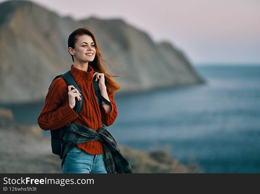 tourism travel woman in sweater with backpack on the back and mountains in the background. High quality photo. tourism travel woman in sweater with backpack on the back and mountains in the background. High quality photo