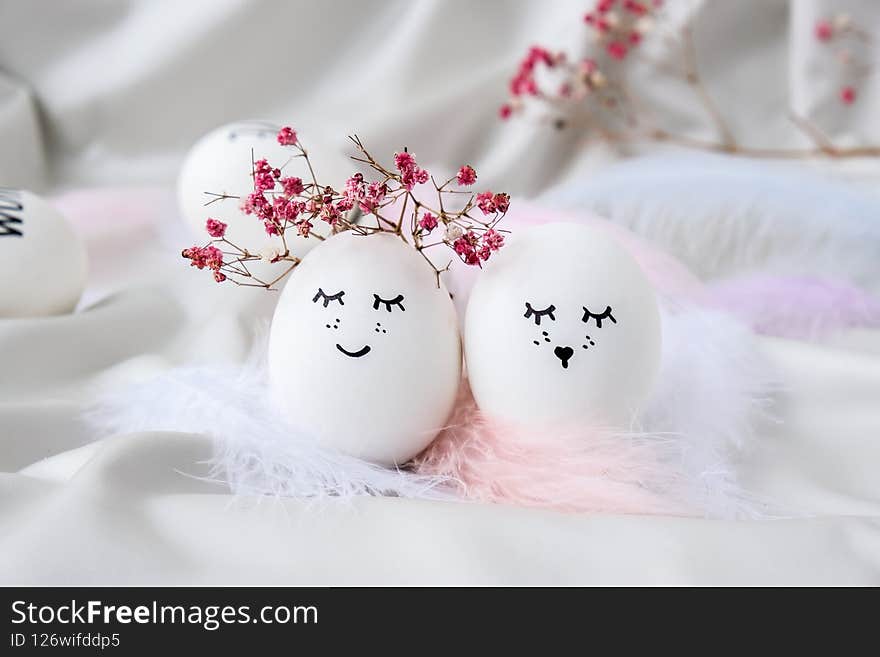 Minimal easter concept. Easter eggs with painted smiley faces and bird feather on pastel background. Wedding couple eggs. Married