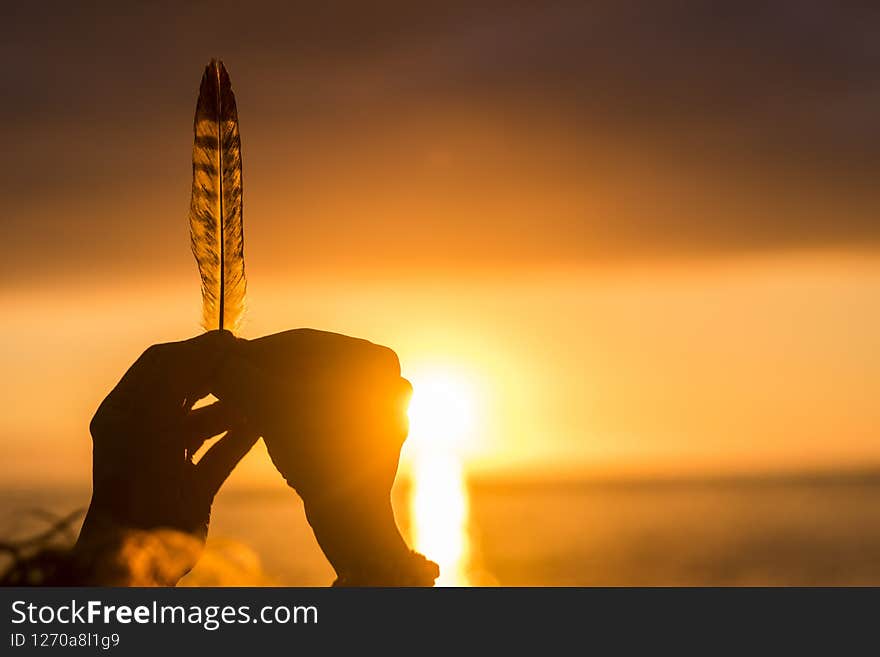 Dream life and hope future concept with close up of hands holding a feather with sunset sunlight in background doing silhouette - summer time and peaceful people lifestyle with love