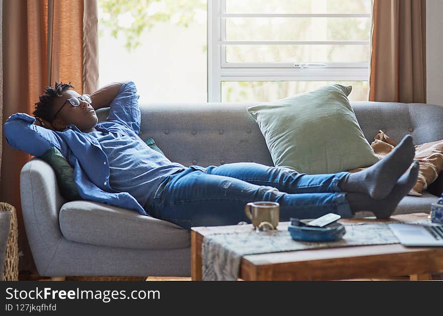 Young man relaxing on his sofa with his feet up on the coffee table. Young man relaxing on his sofa with his feet up on the coffee table