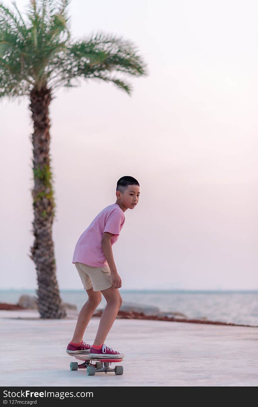 Asian boy happily skating on the beach in the evening.