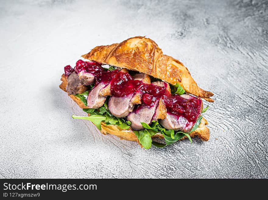 Duck breast Croissant sandwich with steak slices, arugula and sauce. White background. Top View.