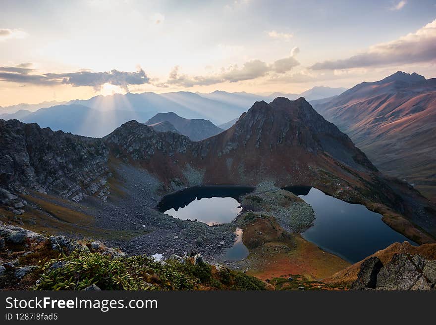 Beautiful mountains at sunset in clouds, gold alpine field, lakes and mountain ranges. Campground by the lake