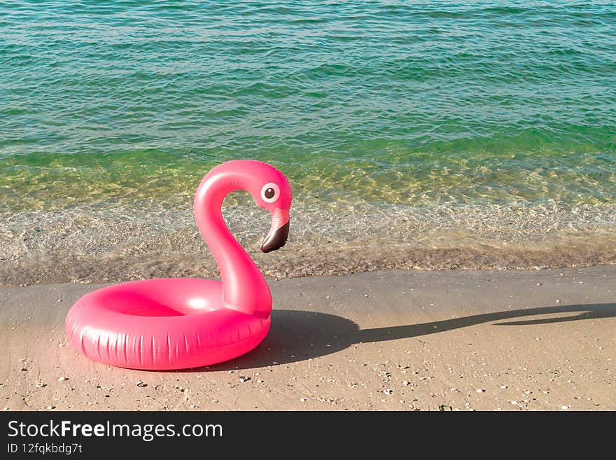 Sea background. Pink inflatable flamingo in blue ocean water for sea summer beach background. Luxury lifestyle travel.