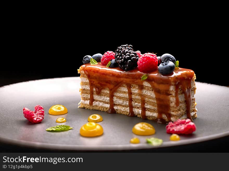 One piece of pie, honey cake with fresh berries, mint, and caramel