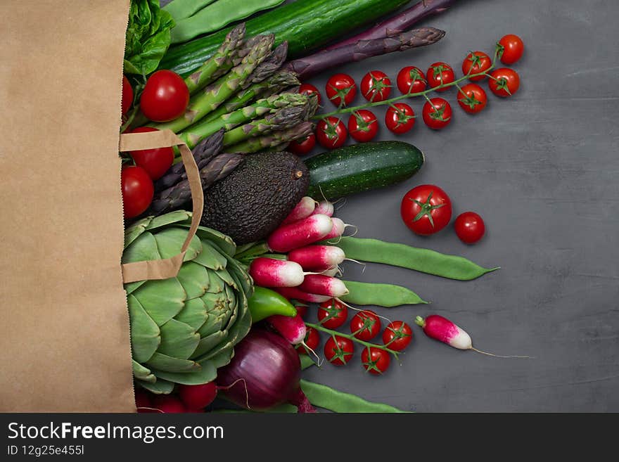 Healthy food background. Healthy food in paper bag, fresh vegetables on grey concrete table. Shopping vegetarian food