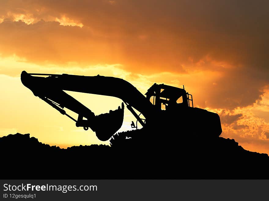 Excavators silhouette are digging the soil in the construction site.