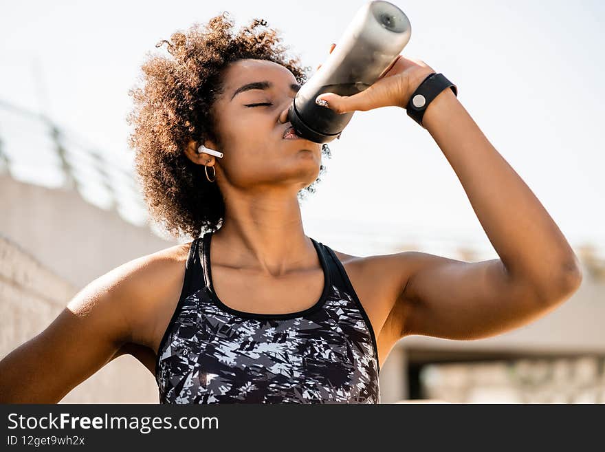 Afro athlete woman drinking water after work out outdoors.