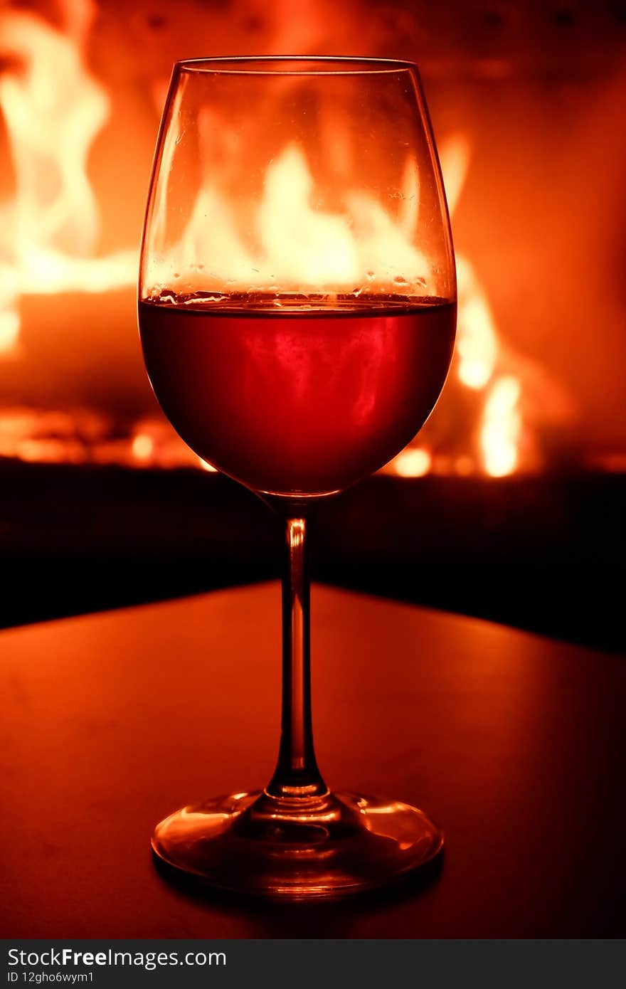 Close-up of a glass of white wine in the backlight of a burning fireplace.